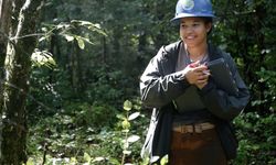 Crew Leader standing in the forest smiling holding a clipboard